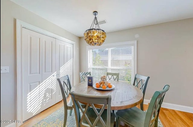 dining space featuring baseboards, a notable chandelier, and light wood-style floors