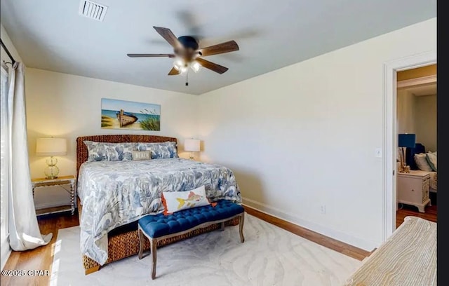 bedroom featuring ceiling fan, wood finished floors, visible vents, and baseboards