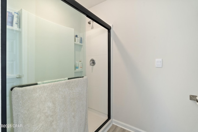 bathroom with baseboards, an enclosed shower, and wood finished floors