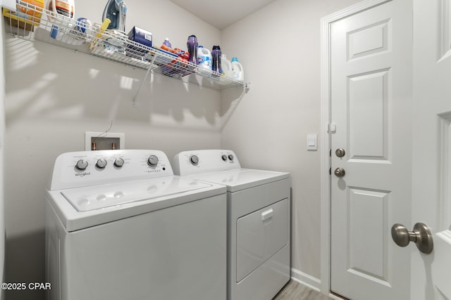 washroom featuring laundry area, baseboards, light wood finished floors, and washer and dryer