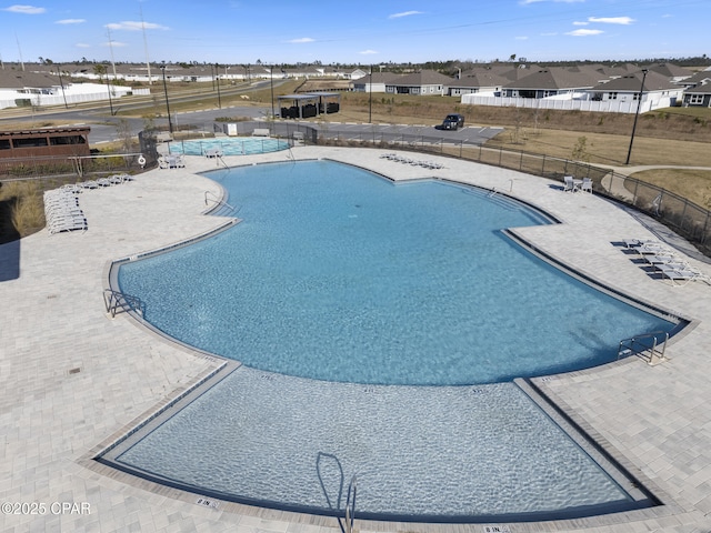 community pool with a patio and fence