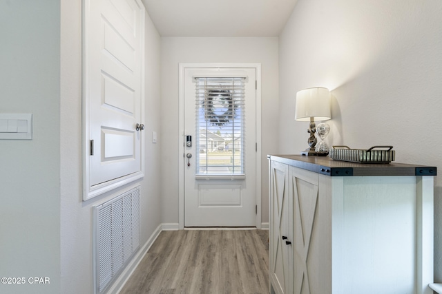 doorway to outside with light wood-style flooring, visible vents, and baseboards