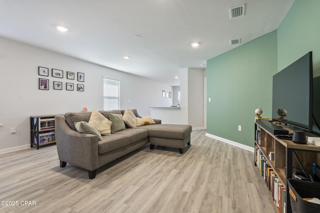 living area with light wood-style floors, baseboards, and visible vents