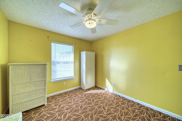 unfurnished bedroom with a textured ceiling, carpet flooring, a ceiling fan, and baseboards