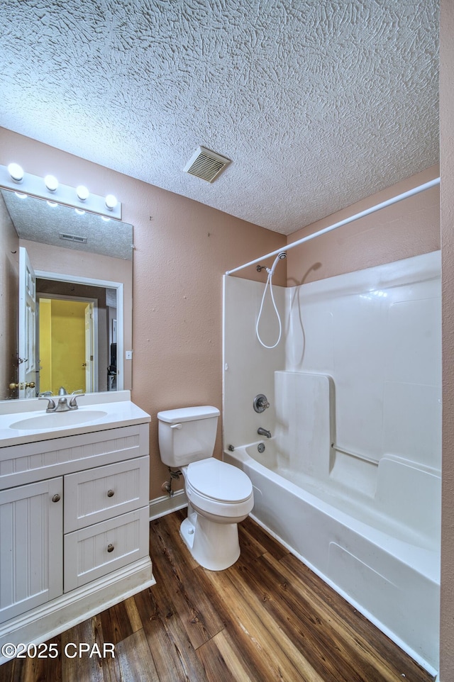 bathroom featuring visible vents, tub / shower combination, a textured ceiling, vanity, and wood finished floors