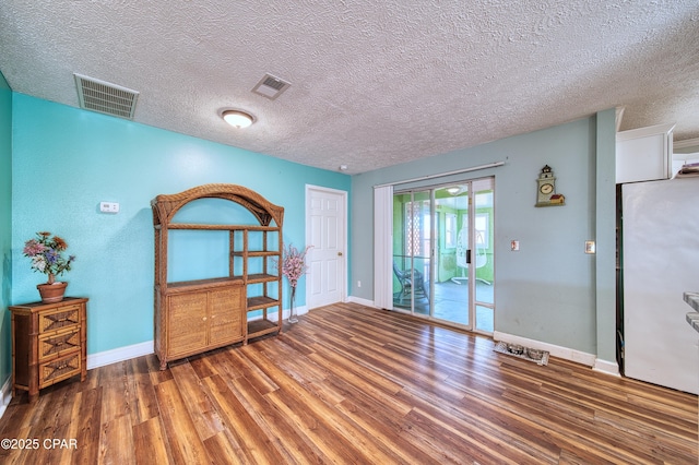 spare room with baseboards, visible vents, and wood finished floors