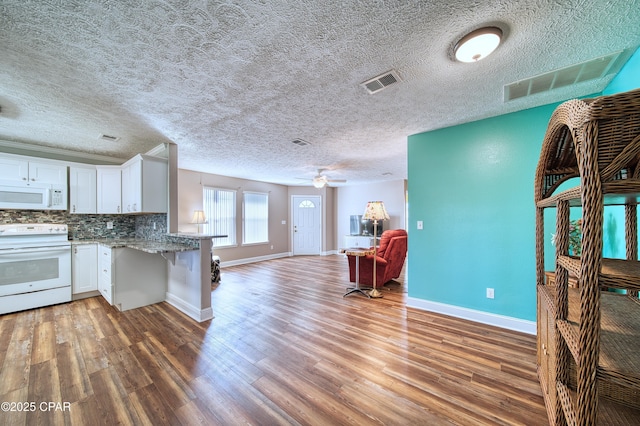 kitchen with visible vents, open floor plan, white cabinetry, white appliances, and a peninsula