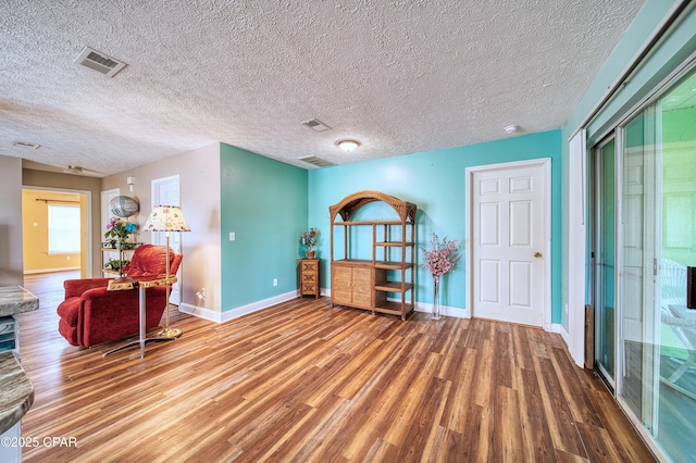 living area with baseboards, visible vents, and wood finished floors