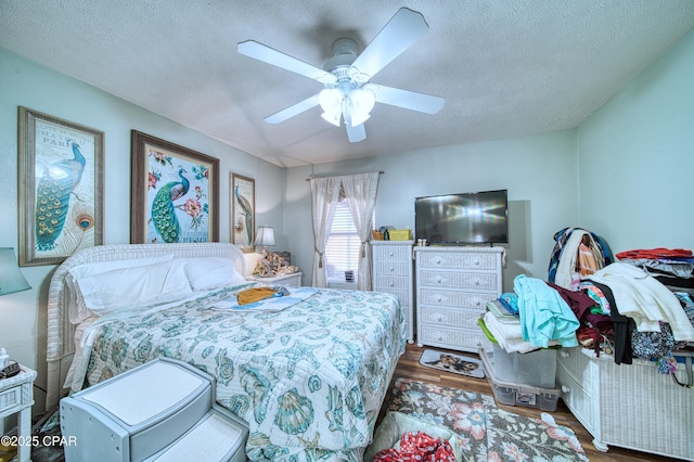 bedroom with a ceiling fan, a textured ceiling, and wood finished floors