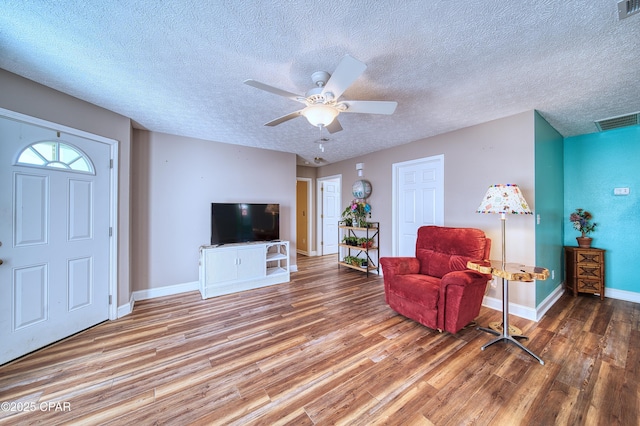 interior space featuring visible vents, a textured ceiling, baseboards, and wood finished floors