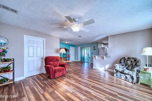 sitting room featuring baseboards, visible vents, ceiling fan, wood finished floors, and a textured ceiling