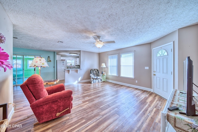 interior space with light wood-style floors, a textured ceiling, baseboards, and a ceiling fan