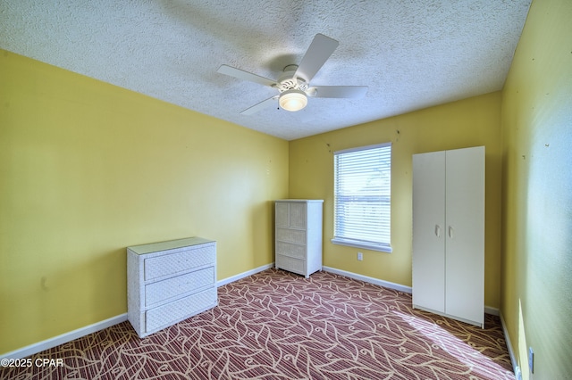 unfurnished bedroom with carpet floors, ceiling fan, baseboards, and a textured ceiling