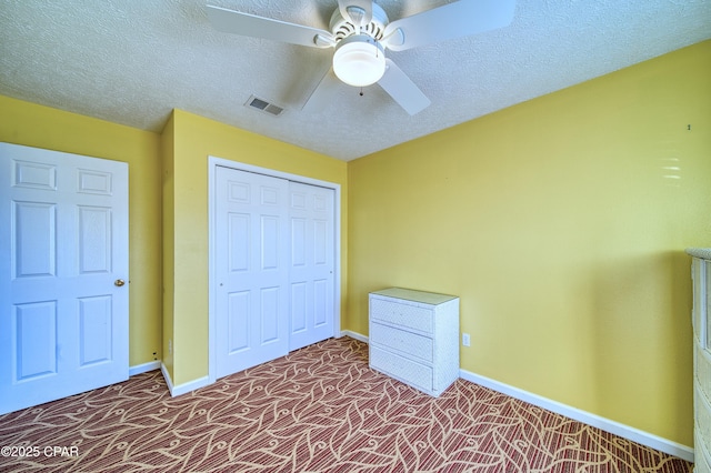 unfurnished bedroom with baseboards, visible vents, carpet, a textured ceiling, and a closet