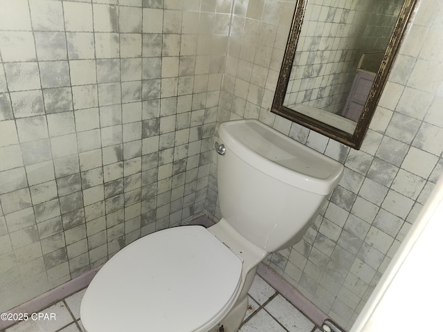 bathroom with toilet and tile walls