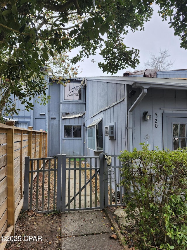 exterior space featuring a gate, fence, and an AC wall unit