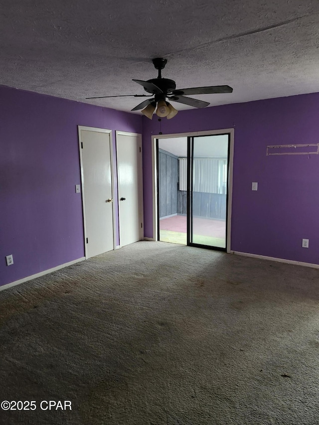 carpeted empty room with ceiling fan, baseboards, and a textured ceiling