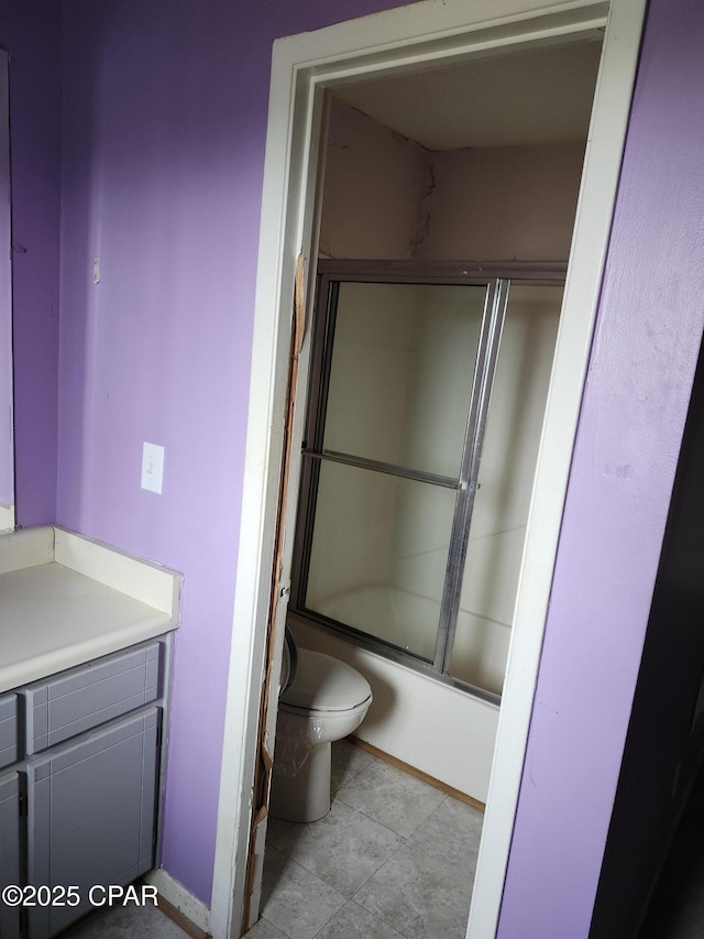 bathroom featuring toilet, combined bath / shower with glass door, and vanity