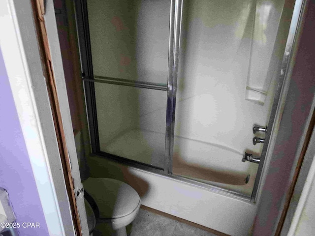 bathroom with toilet and bath / shower combo with glass door