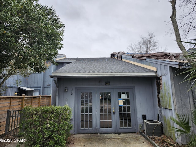 back of property with a shingled roof, fence, central AC unit, and french doors