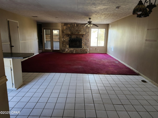 unfurnished living room featuring light carpet, a ceiling fan, a textured ceiling, and a stone fireplace