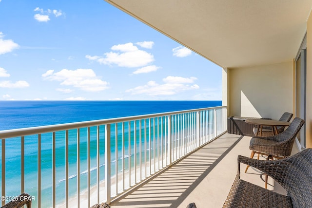 balcony with a water view and a view of the beach