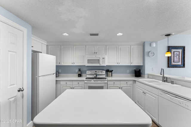 kitchen featuring light countertops, hanging light fixtures, white cabinets, a sink, and white appliances