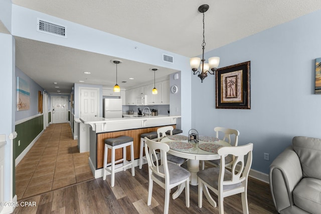 dining room featuring a textured ceiling, dark wood-type flooring, and visible vents