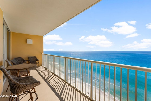 balcony featuring a view of the beach and a water view