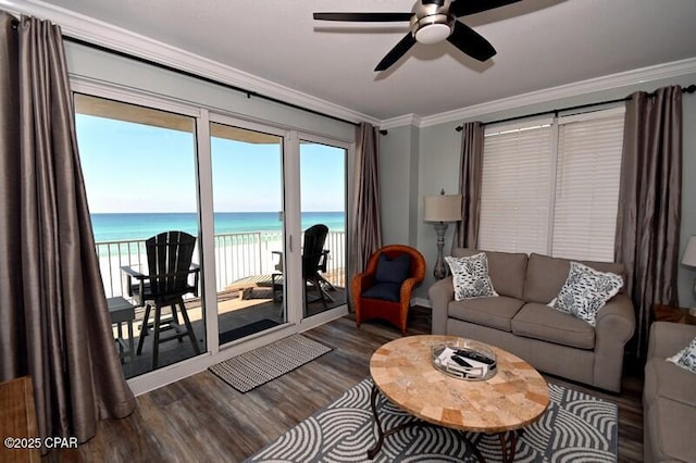 living area featuring ceiling fan, a water view, a beach view, dark wood-style floors, and crown molding