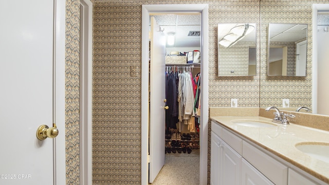bathroom with double vanity, a sink, a walk in closet, and visible vents