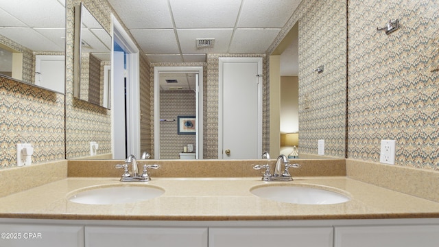 full bathroom with double vanity, a drop ceiling, a sink, and visible vents