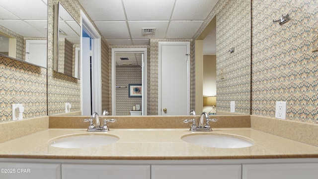 bathroom with double vanity, visible vents, a sink, and a paneled ceiling