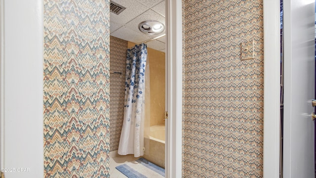 full bathroom with shower / tub combo, tile patterned flooring, visible vents, and a drop ceiling