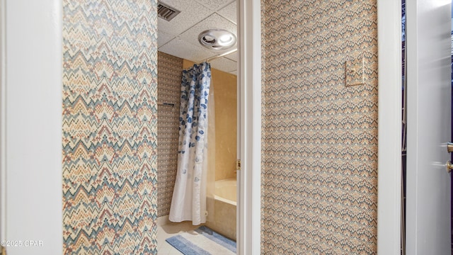 bathroom with tile patterned floors, visible vents, and a drop ceiling
