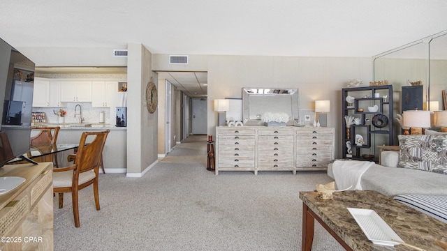 living area featuring baseboards, visible vents, and light colored carpet