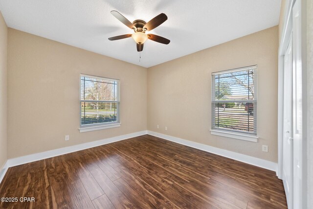 empty room with ceiling fan, baseboards, and dark wood-type flooring