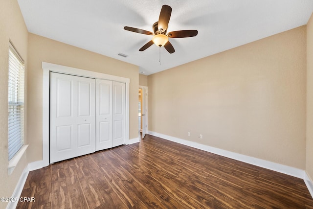 unfurnished bedroom with dark wood-style floors, baseboards, and a closet