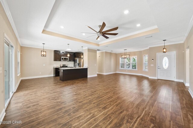 unfurnished living room featuring dark wood-style floors, crown molding, a raised ceiling, baseboards, and ceiling fan with notable chandelier