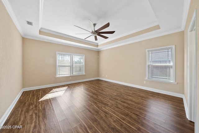 spare room with dark wood-style floors, a tray ceiling, visible vents, and ceiling fan