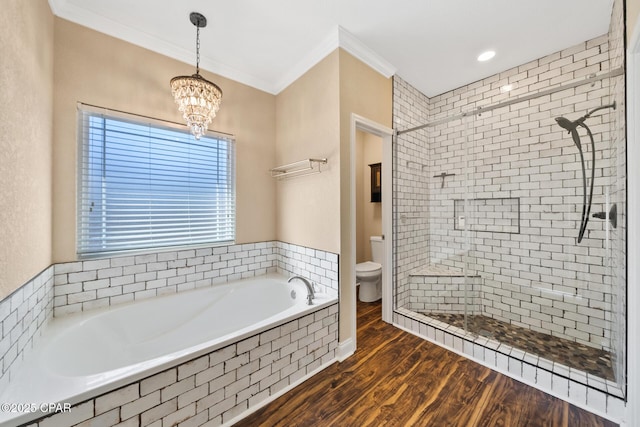 bathroom with toilet, wood finished floors, ornamental molding, a bath, and a stall shower