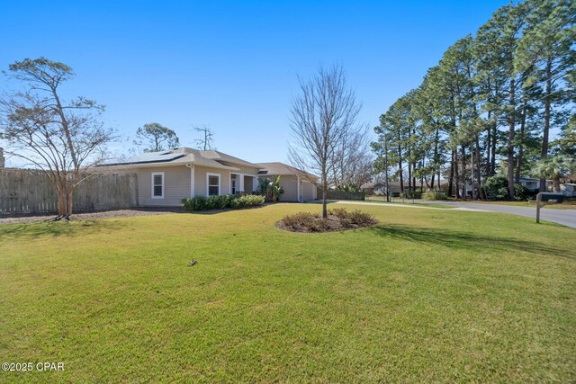 view of yard with a garage, fence, and driveway