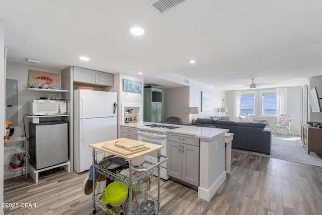 kitchen with white appliances, visible vents, gray cabinets, and wood finished floors