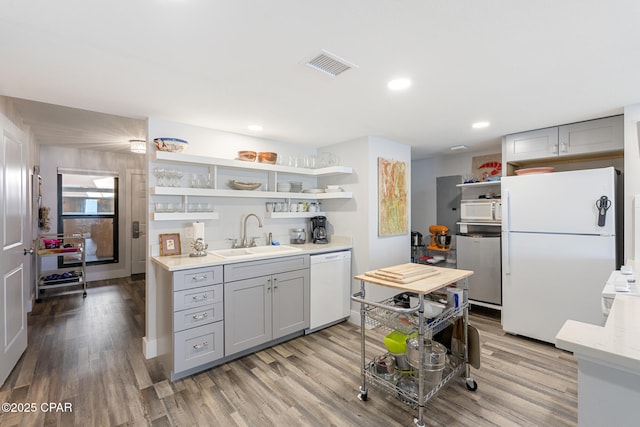 kitchen with white appliances, visible vents, gray cabinets, open shelves, and a sink