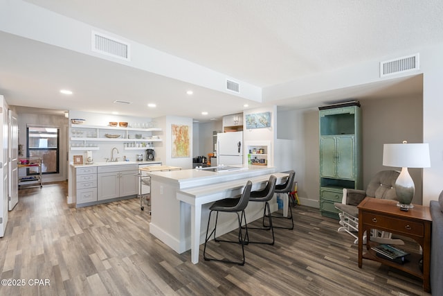 kitchen featuring freestanding refrigerator, visible vents, light wood-style flooring, and open shelves