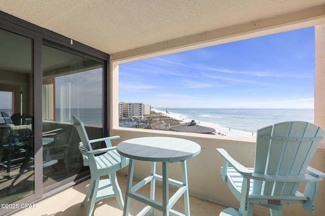 balcony featuring a beach view and a water view