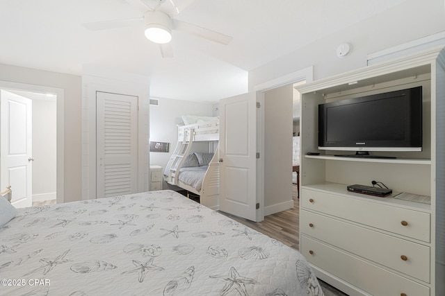 bedroom with baseboards, visible vents, a ceiling fan, wood finished floors, and a closet