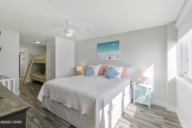 bedroom featuring a ceiling fan, a closet, baseboards, and wood finished floors