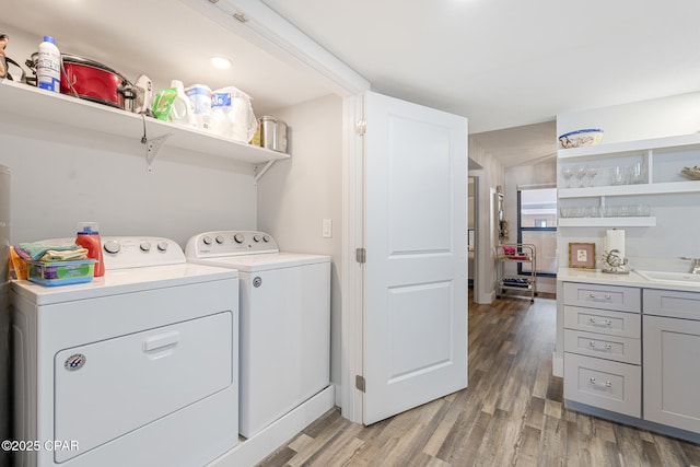 clothes washing area with laundry area, light wood-type flooring, a sink, and washer and dryer