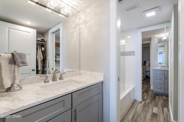 full bathroom with a spacious closet, visible vents, wood finished floors, and vanity